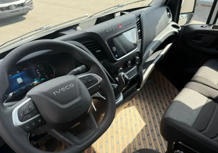 Vue intérieure de l’IVECO Daily 35S18 2026, montrant le volant, tableau de bord et siège passager en tissu gris.