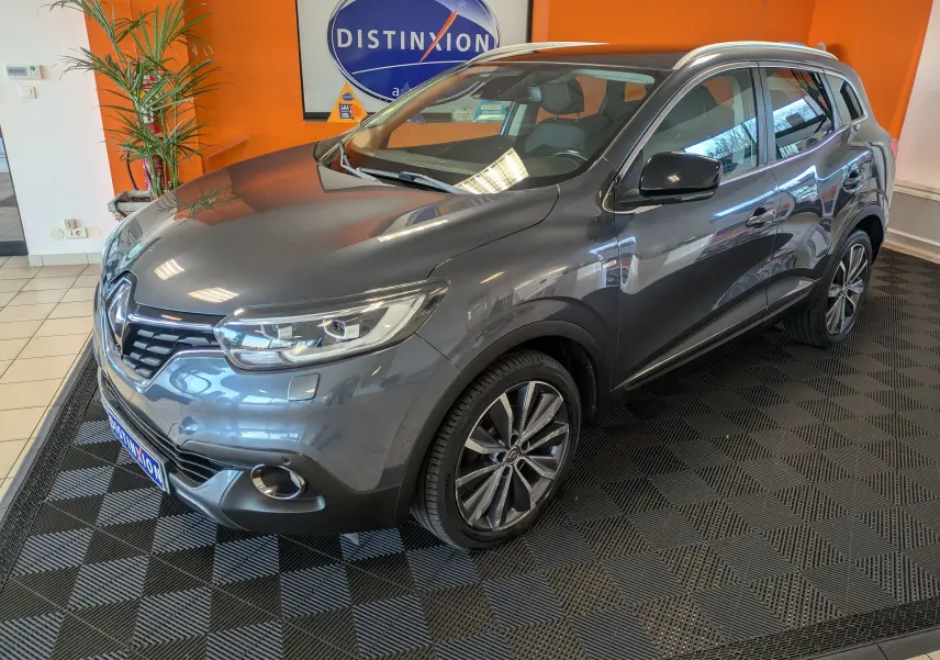 Renault Kadjar gris 3/4 avant droit en intérieur, avec jantes alliage bi-ton et toit ouvrant visible.