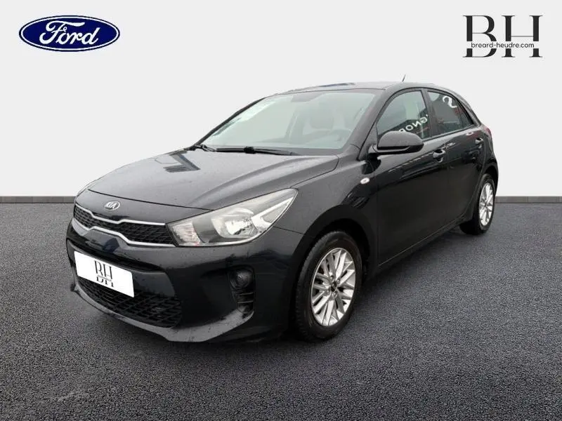 KIA Rio noir Ébène vue 3/4 avant droit, avec calandre chromée et jantes alliage visibles.