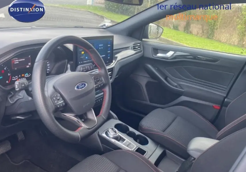 Vue intérieure côté conducteur de la Ford Focus 2024 gris foncé, avec volant sport, écran tactile et accoudoir central.