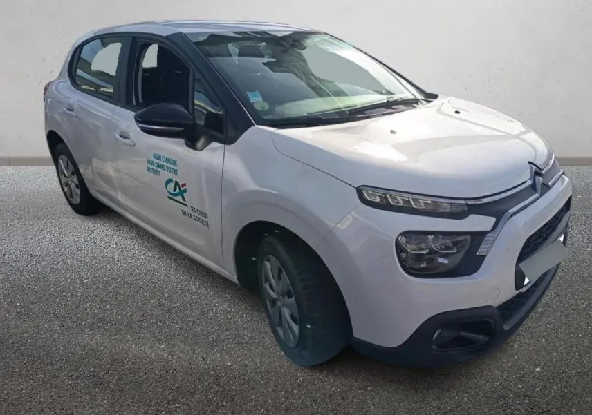Citroën C3 blanche vue 3/4 avant droit avec logo Crédit Agricole sur la porte avant.