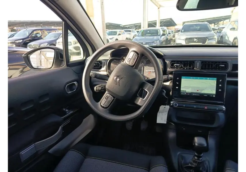 Vue intérieure du poste de conduite de la Citroën C3 2021, tableau de bord noir avec écran GPS tactile et volant multifonction.