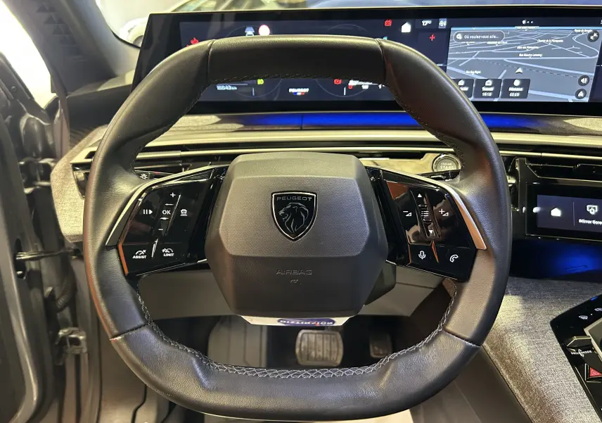 Vue rapprochée du volant cuir noir du Peugeot 3008 2024 avec tableau de bord numérique et écran tactile panoramique.