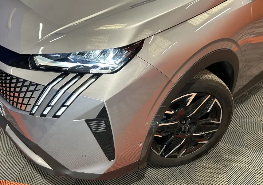 Vue 3/4 avant droit du Peugeot 3008 gris Artense, mettant en valeur le phare LED et la jante noire brillante.
