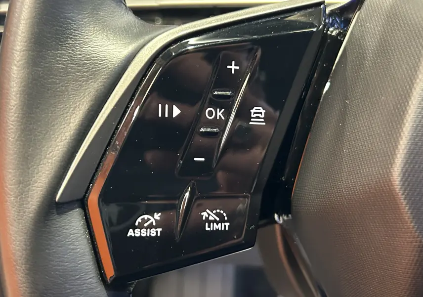 Gros plan sur les commandes noires au volant côté gauche du Peugeot 3008 gris Artense, avec boutons de régulateur et limiteur.
