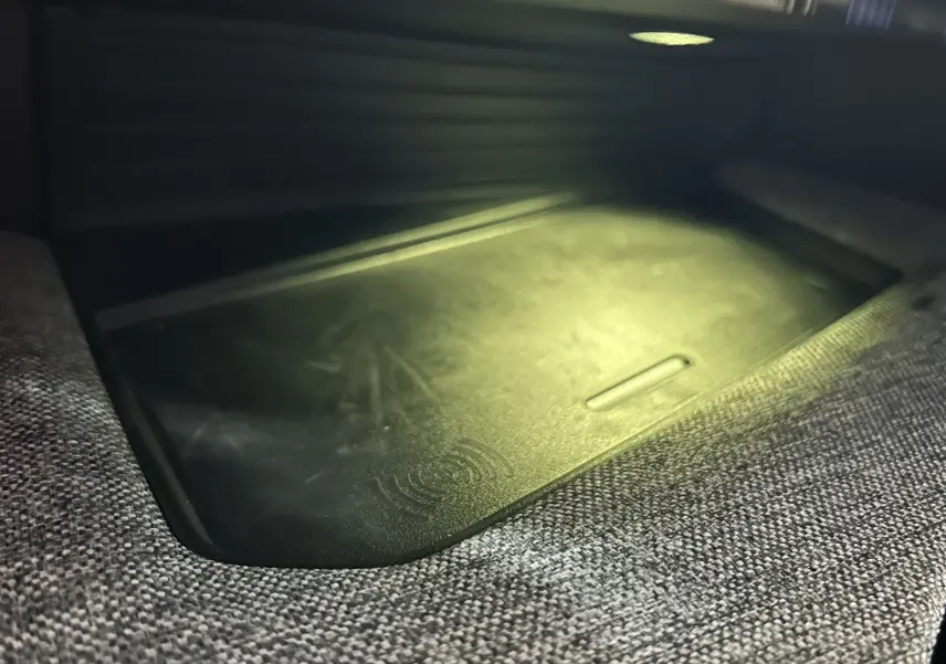 Gros plan sur le chargeur à induction intégré dans l'accoudoir central du Peugeot 3008 gris Artense 2024.