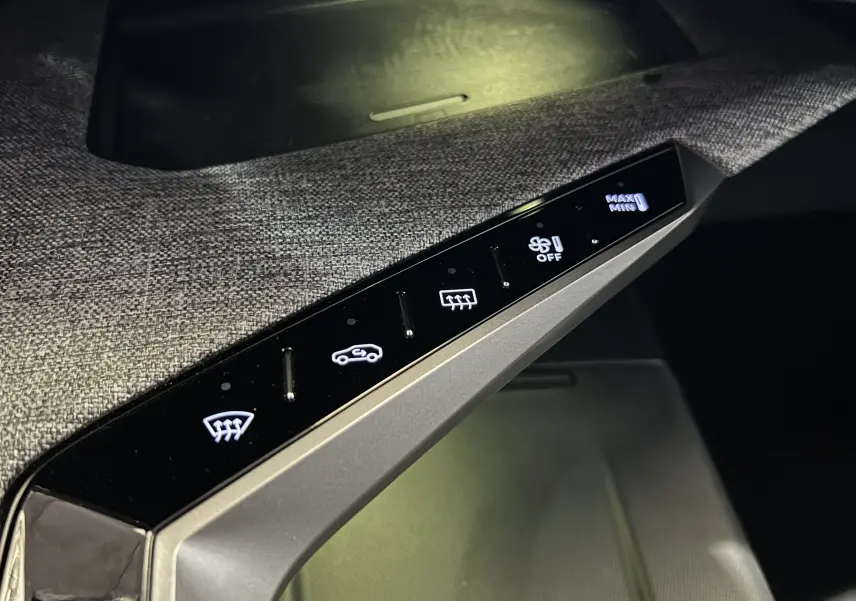 Gros plan sur la console intérieure tactile du Peugeot 3008 III Hybrid 145, avec commandes de climatisation éclairées.