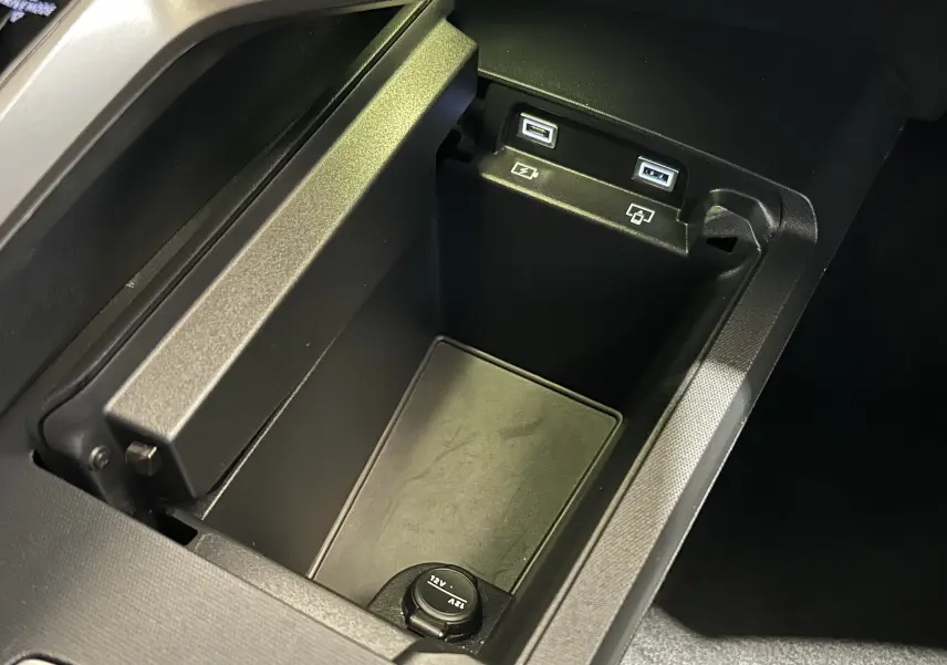 Gros plan sur la console centrale noire du Peugeot 3008 III Hybrid avec ports USB et prise 12V intégrés.