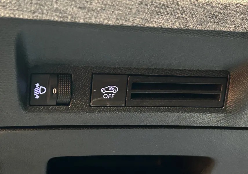 Gros plan sur les commandes intérieures du Peugeot 3008 gris Artense, avec réglage des phares et bouton d'assistance désactivée.