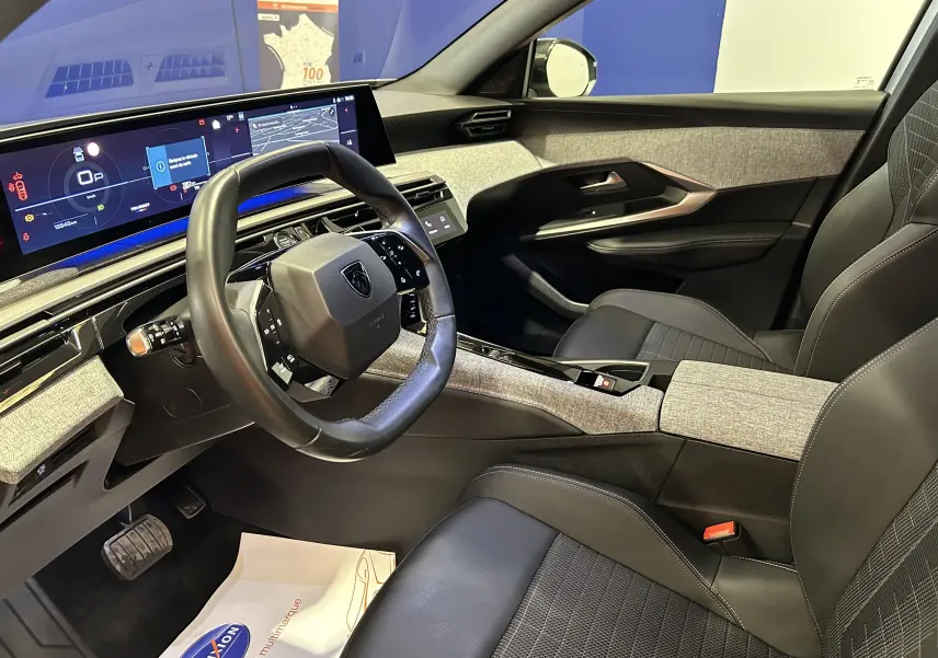 Vue intérieure côté conducteur du Peugeot 3008 hybride 2024, avec i-Cockpit numérique et sellerie cuir/gris clair.
