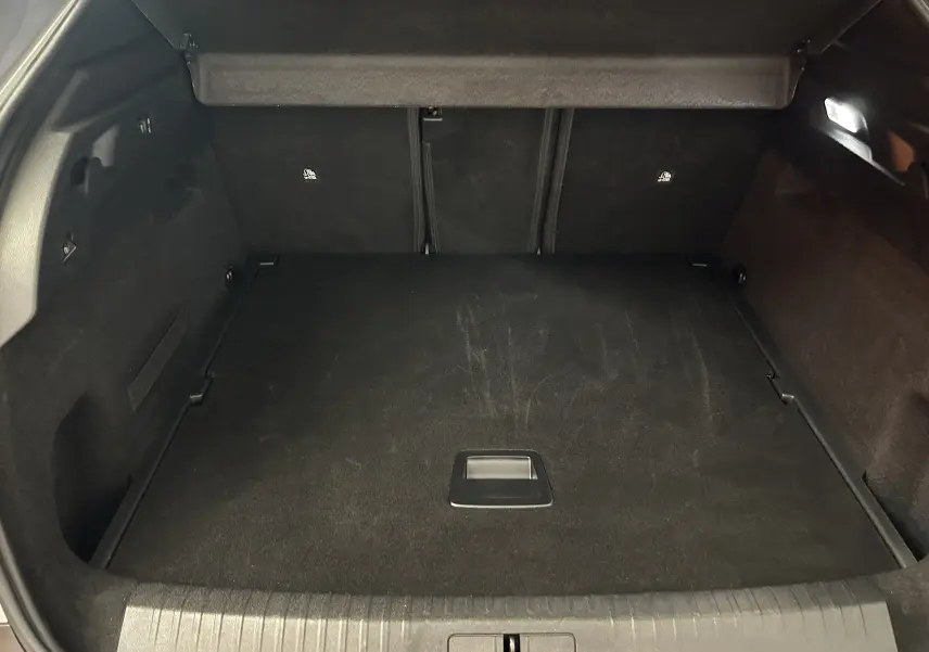 Coffre spacieux et propre du Peugeot 3008 III Hybrid 145, vue intérieure arrière avec revêtement noir uniforme.