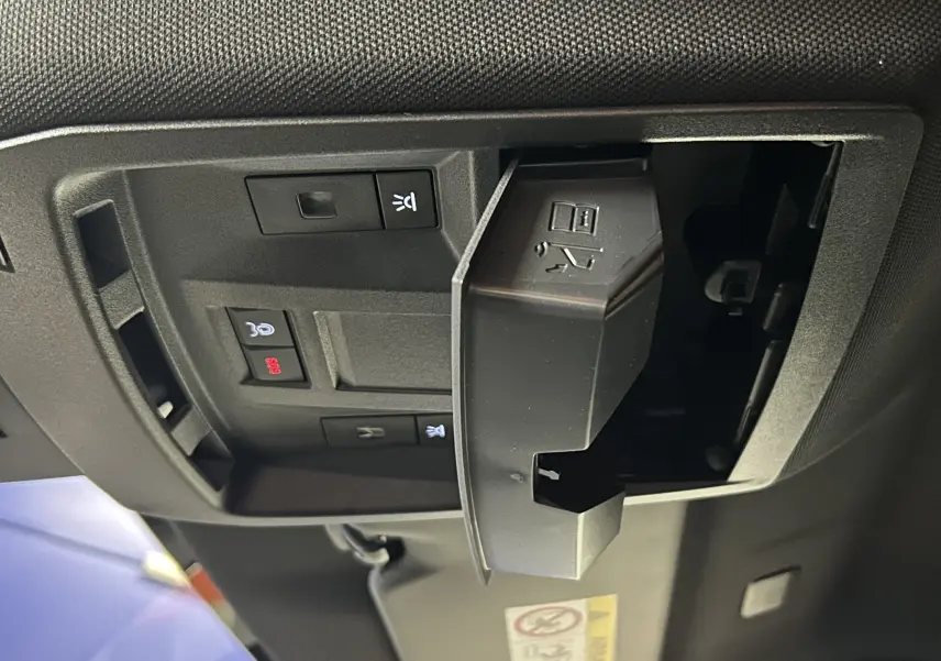 Vue intérieure du plafond de la Peugeot 3008 III Hybrid gris Artense, montrant les commandes d’éclairage et un compartiment ouvert.