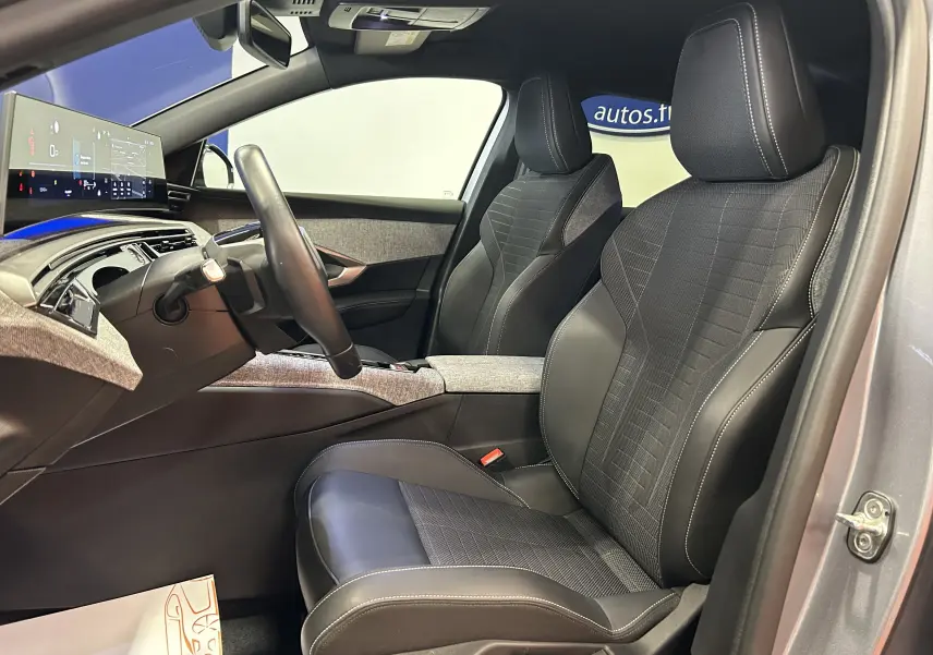 Vue intérieure côté conducteur du Peugeot 3008 gris Artense 2024, sièges cuir et tissu, tableau de bord avec écran panoramique.