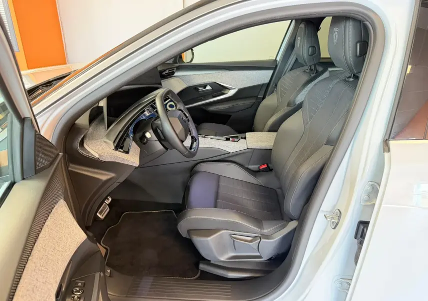 Vue intérieure côté conducteur du Peugeot 5008 Hybrid blanc Okenite, sièges tissu/tep gris avec surpiqûres Iced Clay.