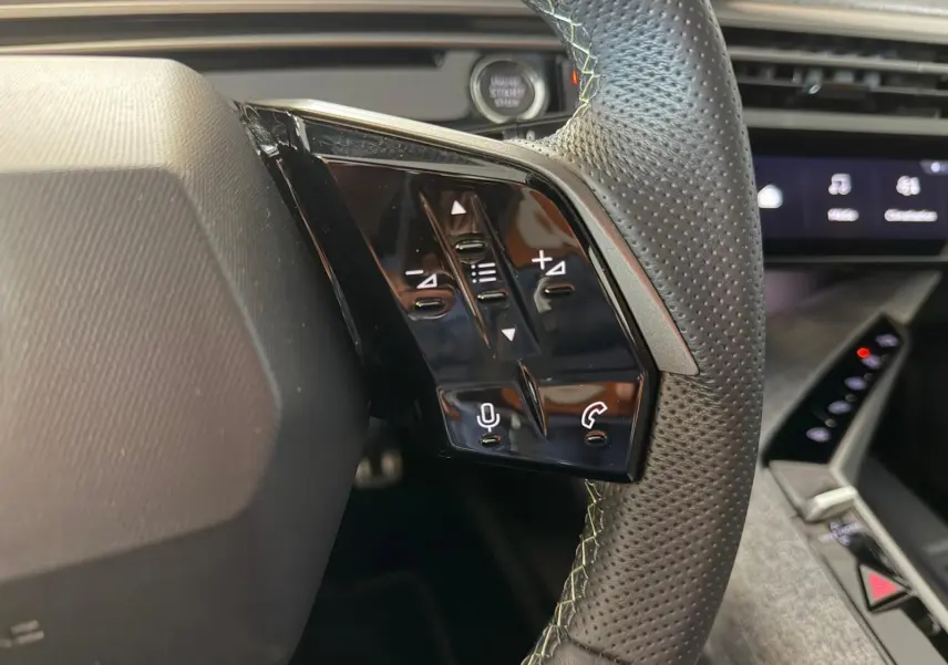 Gros plan sur les commandes au volant à droite du Peugeot 5008 Hybrid 145 e-DCS6 GT, intérieur noir avec surpiqûres claires.