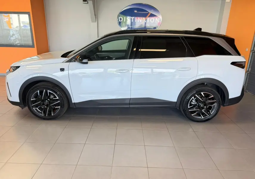 Peugeot 5008 Hybrid 145 e-DCS6 GT blanc Okenite toit noir, vue profil côté gauche en intérieur showroom.