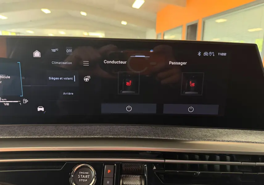 Écran tactile du tableau de bord du Peugeot 5008 Hybrid 145 GT montrant les commandes des sièges chauffants.