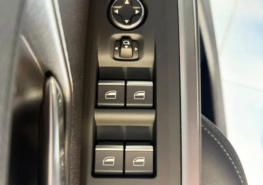 Vue rapprochée des commandes de lève-vitres et rétroviseurs côté conducteur du Peugeot 5008 Hybrid 145 e-DCS6 GT.