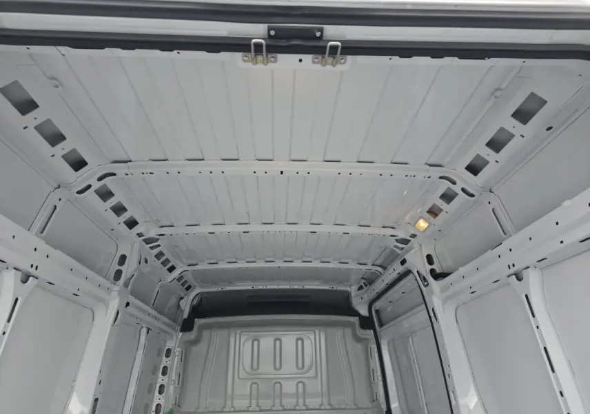 Vue intérieure du coffre blanc du Peugeot Boxer Fourgon 2025, montrant la structure tôlée et l'éclairage intérieur.