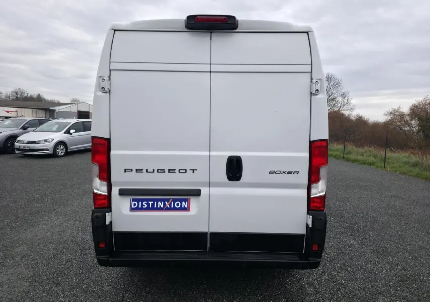 Vue arrière d'un Peugeot Boxer Fourgon blanc avec portes battantes et feux rouges visibles.