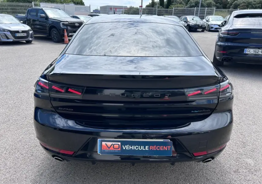 Vue arrière d'une Peugeot 508 Hybrid 225 noire de 2024, avec feux LED distinctifs et double sortie d'échappement.