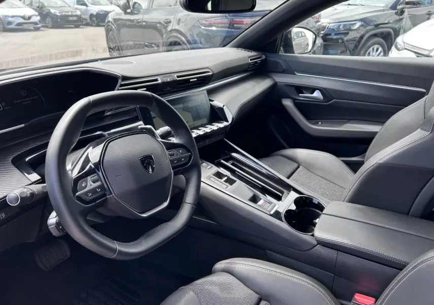 Vue intérieure côté conducteur de la Peugeot 508 Hybrid 225 e-EAT8 Allure 2024 avec volant cuir et écran tactile.