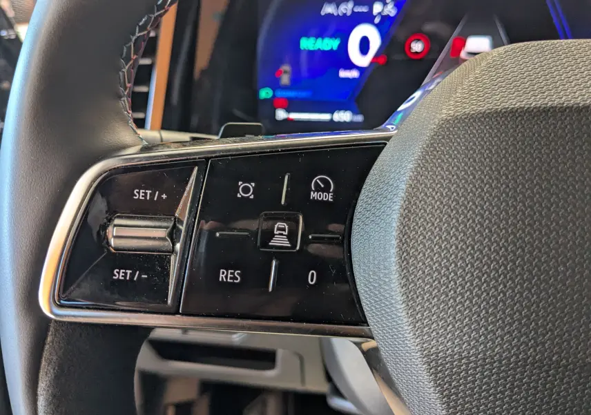 Gros plan sur les commandes à gauche du volant du Renault Espace VI E-Tech, avec affichage digital en arrière-plan.