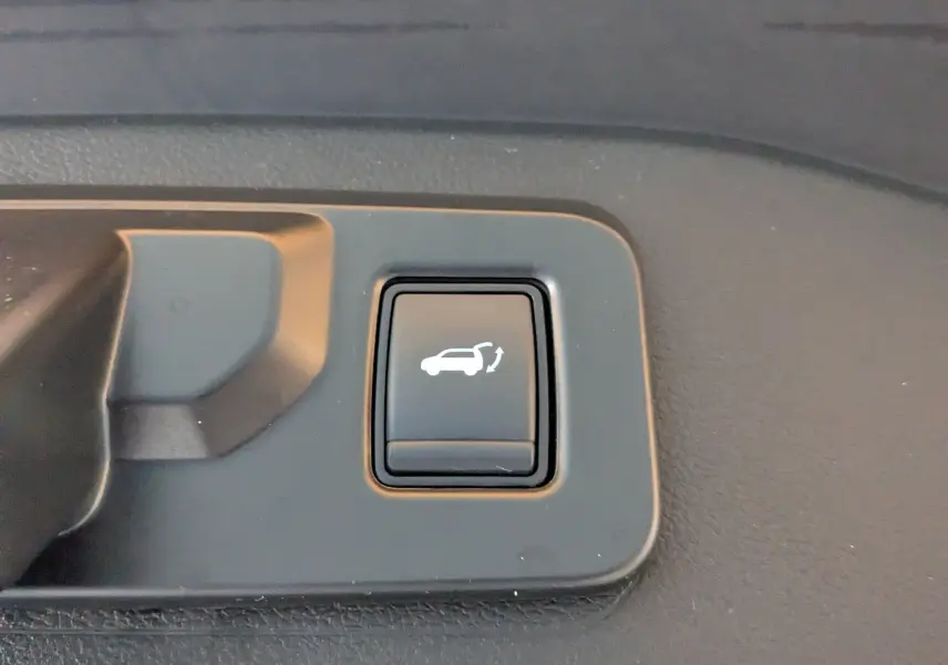Bouton intérieur noir avec symbole blanc d'ouverture de hayon, détail du Renault Espace VI E-Tech Full Hybrid 2025.