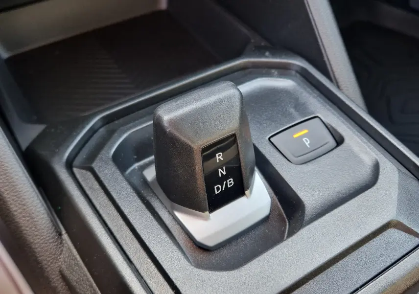 Gros plan sur le levier de vitesses automatique noir et gris du Dacia Duster 1.8 Hybrid 155, avec bouton de parking éclairé.
