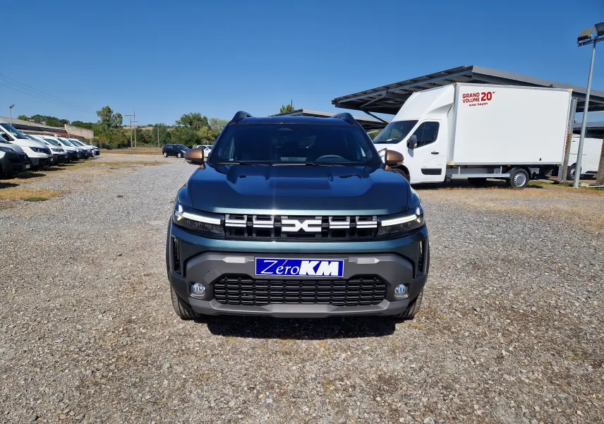 Vue frontale d'un Dacia Duster 1.8 Hybrid 155 Extreme vert cèdre, avec calandre moderne et plaque "Zero KM".