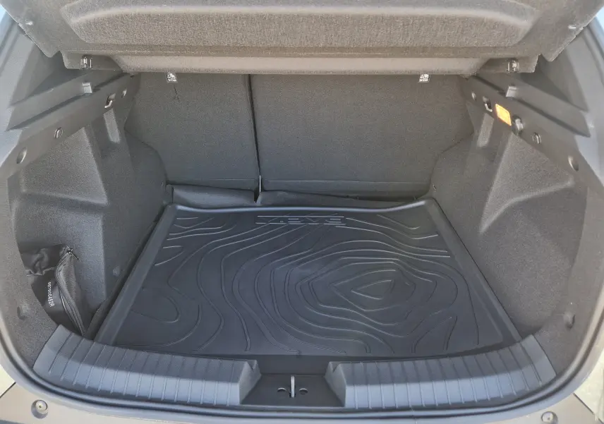 Coffre ouvert du Dacia Duster 1.8 Hybrid 155 2026, vue intérieure montrant un tapis de sol noir avec reliefs.