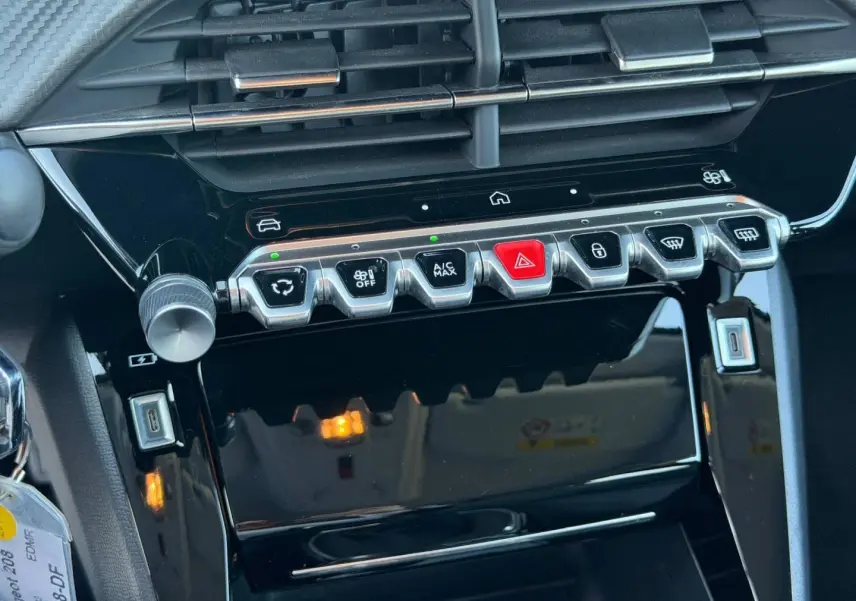 Vue rapprochée de la console centrale de la Peugeot 208 1.2 100ch Allure, boutons argentés et écran tactile noir.