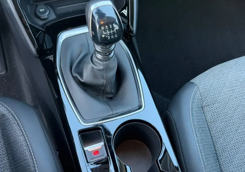 Gros plan sur la console centrale de la Peugeot 208 2025, avec levier de vitesse manuel et sellerie tissu gris.