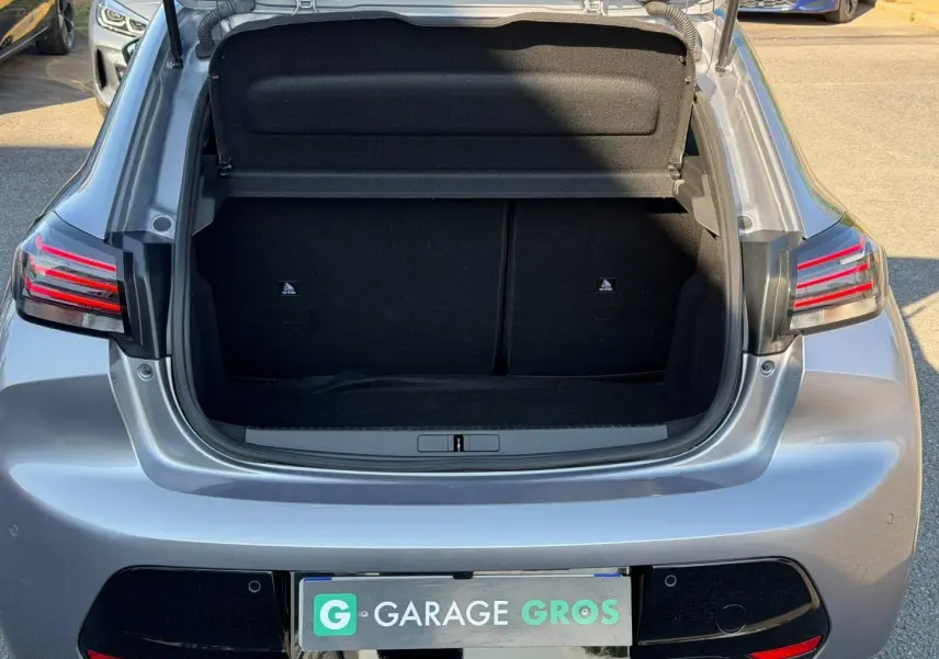 Coffre ouvert vu de l'arrière d'une Peugeot 208 1.2 100ch gris Artense avec feux arrière LED distinctifs.