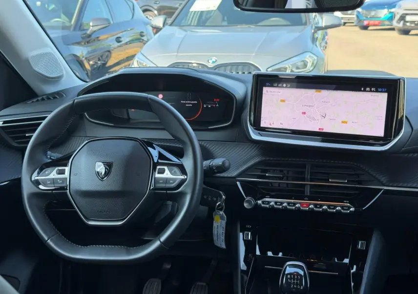 Vue intérieure frontale du tableau de bord et volant noir du Peugeot 208 1.2 100ch avec écran tactile et boîte manuelle.