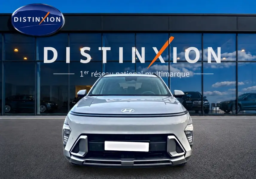 Vue avant d'un Hyundai Kona gris 2025 avec calandre moderne et logo Hyundai visible, devant une vitrine Distinxion.