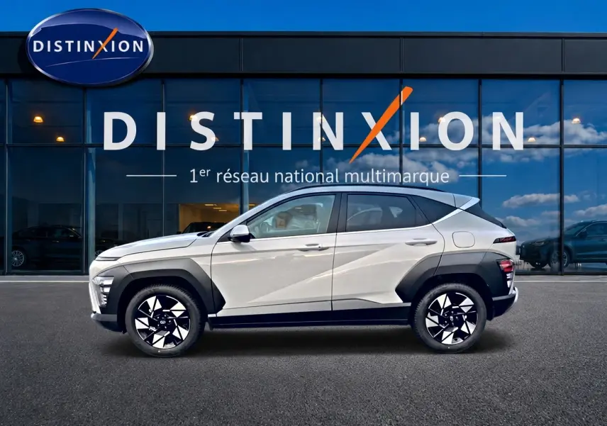 Vue de profil côté gauche d’un Hyundai Kona gris 2025 avec protections noires et jantes alliage bicolores devant un bâtiment Distinxion.