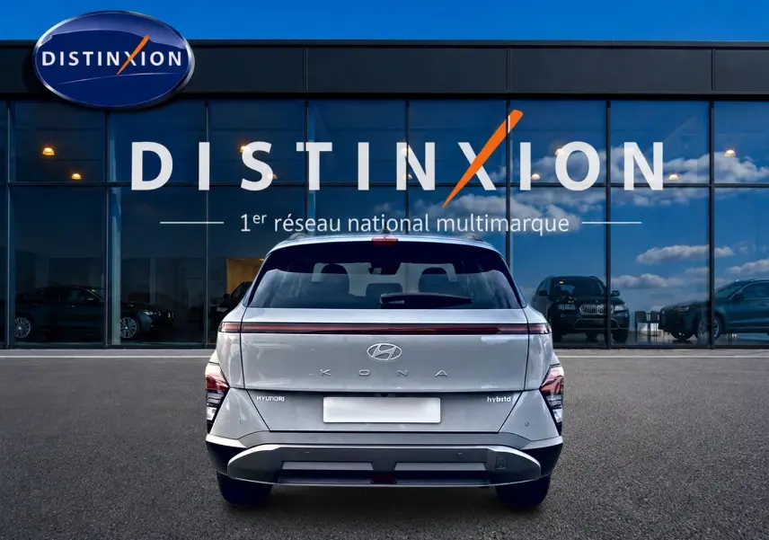 Vue arrière d'un Hyundai Kona gris 2025 hybride, avec feux arrière à LED et logo distinctif sur fond de vitrine Distinxion.