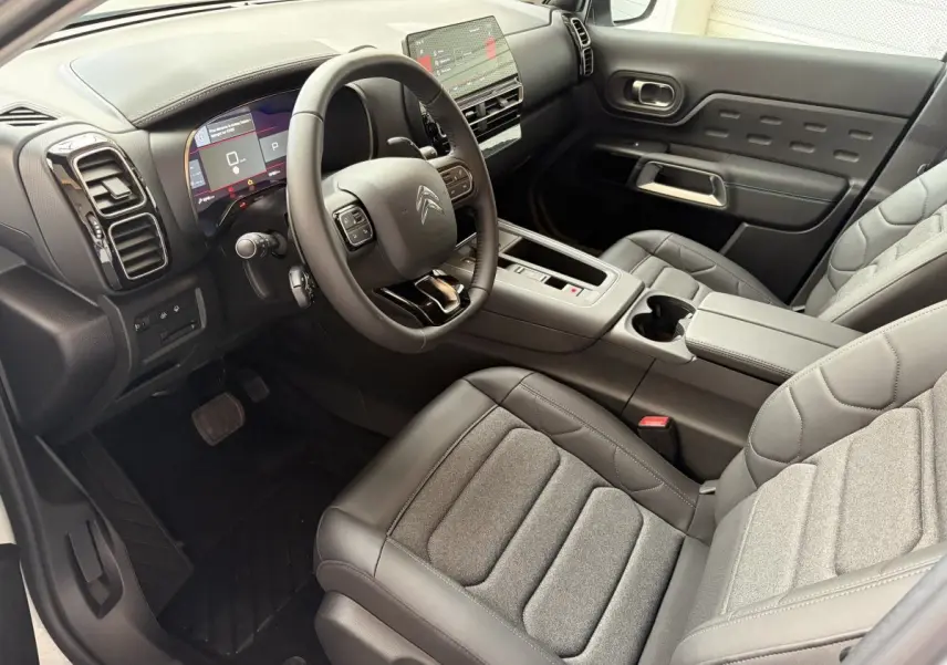 Vue intérieure côté conducteur du Citroën C5 Aircross 2025, sièges gris et tableau de bord avec écran tactile.