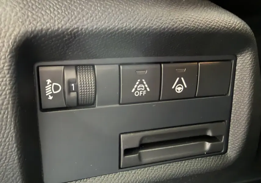 Gros plan sur les commandes noires du tableau de bord du Citroën C5 Aircross, avec réglage phares et aides à la conduite.
