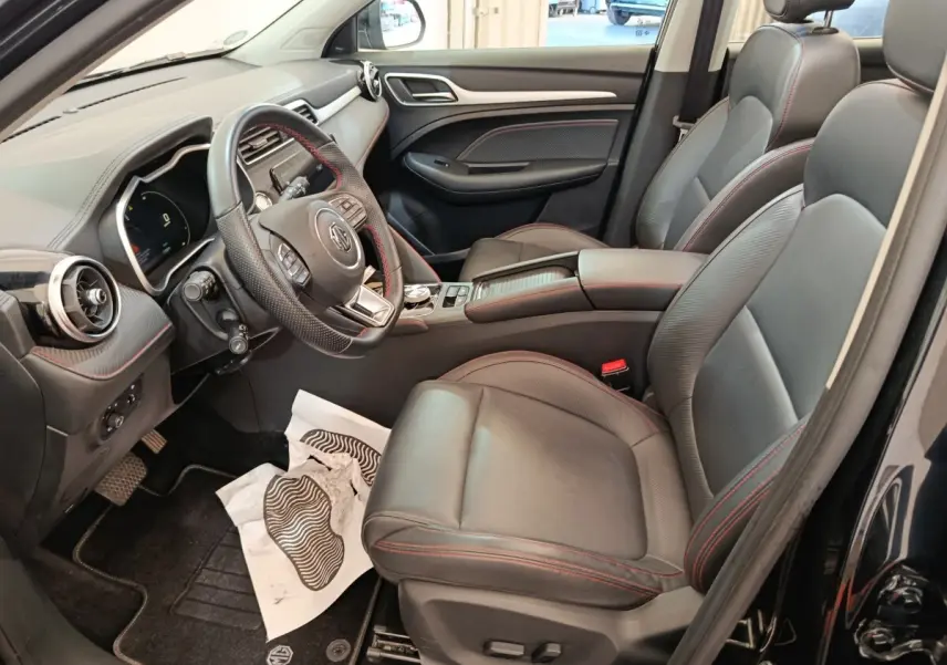 Intérieur noir du MG ZS Luxury 2024 vu côté conducteur, avec sièges cuir et volant multifonctions.