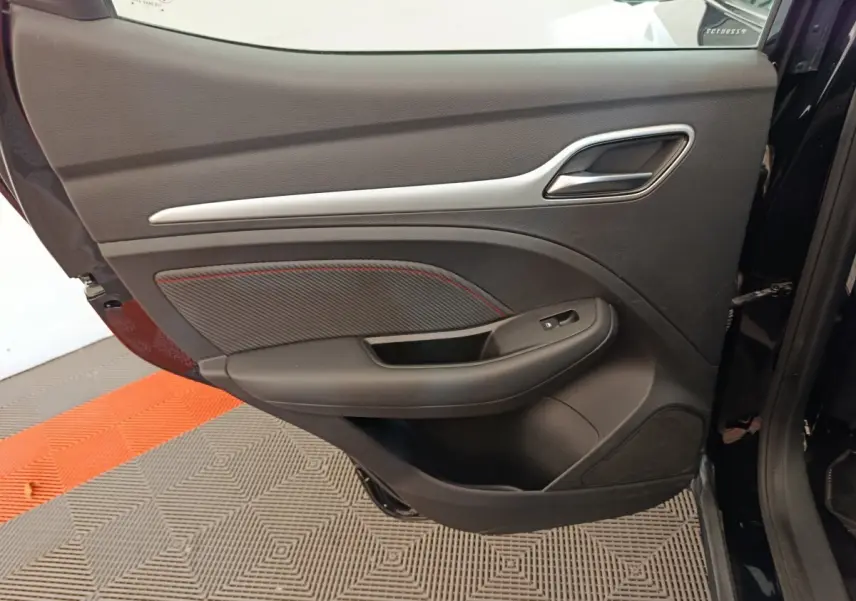 Vue intérieure de la porte arrière gauche noire du MG Motor ZS Luxury 2024 avec insert décoratif et bouton de vitre électrique.