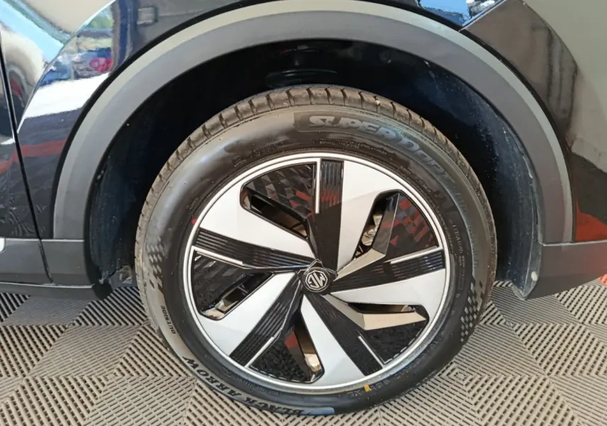 Gros plan sur la roue avant droite noire du MG ZS Luxury 70kWh 2024 avec jante au design géométrique bicolore.
