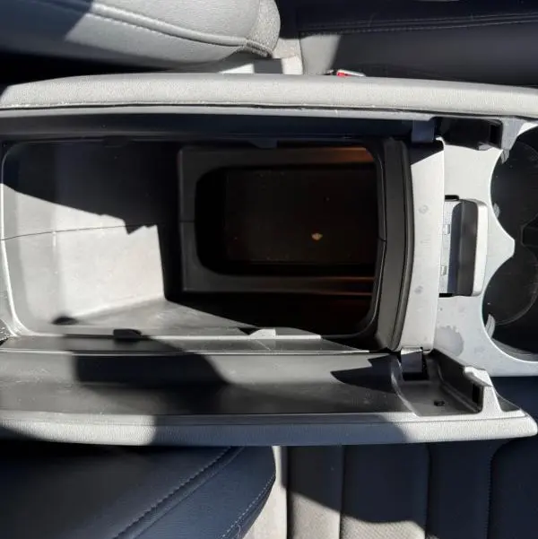 Vue plongeante sur la console centrale noire ouverte du Citroën C5 Aircross hybride 2024, montrant le rangement intérieur.