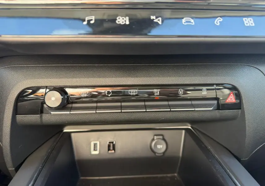 Gros plan sur la console centrale du Citroën C5 Aircross Hybride 2024 noire, montrant les commandes climatisation et ports USB.