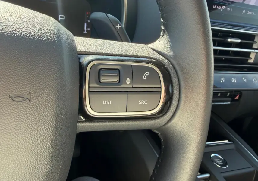 Gros plan sur les commandes au volant du Citroën C5 Aircross Hybride 2024, intérieur noir avec boutons fonction téléphone et liste.