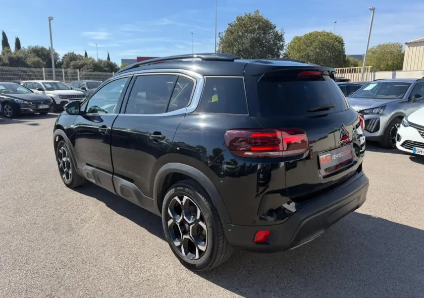 Vue 3/4 arrière droite d'un Citroën C5 Aircross hybride noir 2024 avec jantes distinctives et vitres teintées.