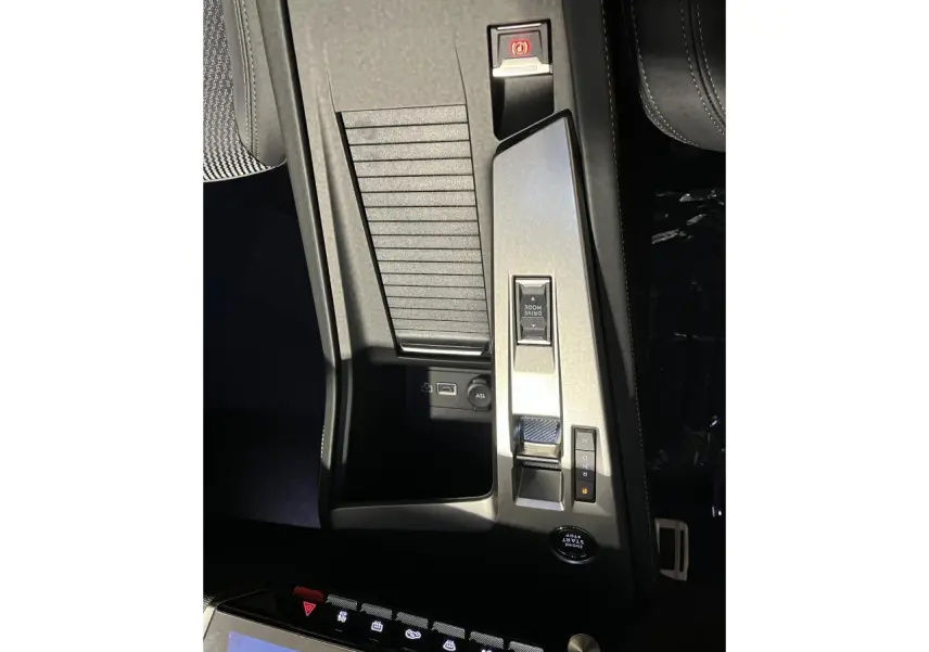 Vue plongeante de la console centrale gris aluminium de la Peugeot 308 GT 2024 avec commandes de boîte auto et prise 12V visible