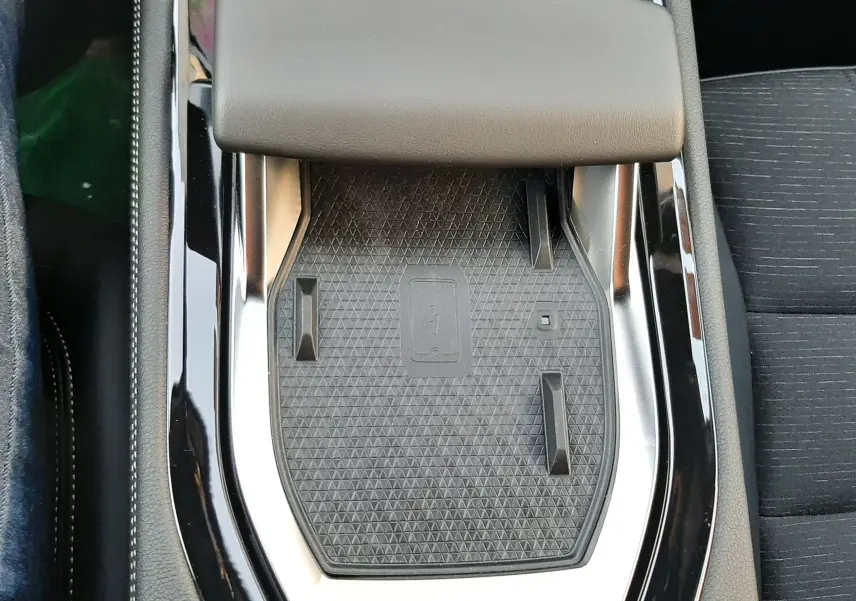 Gros plan sur le chargeur sans fil et accoudoir noir dans l'habitacle du Renault Austral blanc nacré 2025.