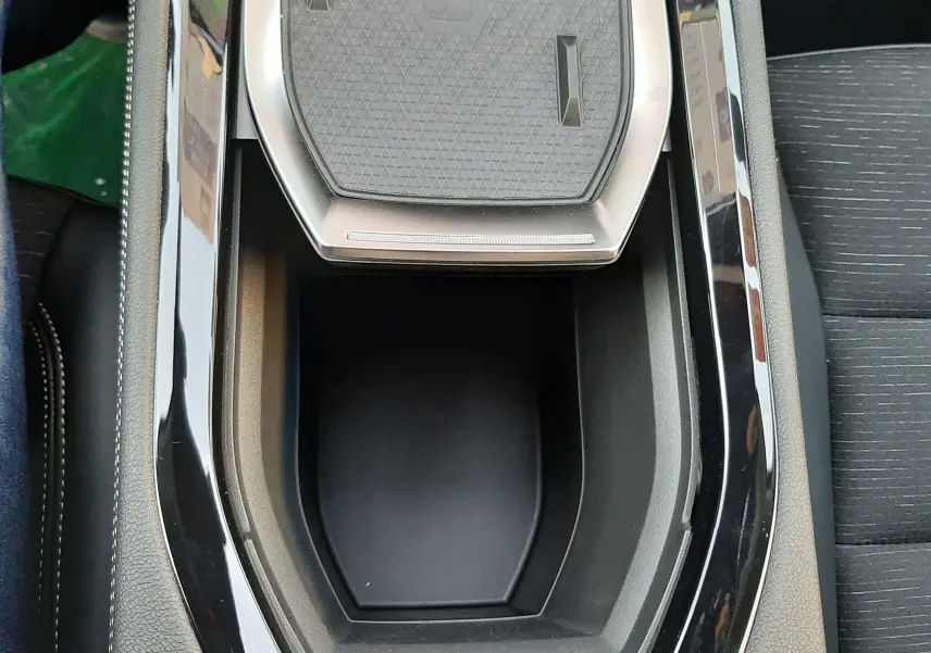 Vue plongeante sur la console centrale noire brillante du Renault Austral E-Tech Hybrid 2025 avec rangement et surface texturée.